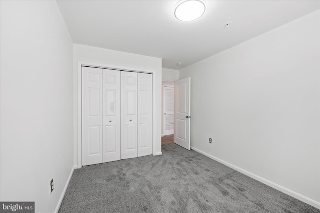 unfurnished bedroom with baseboards, carpet flooring, and a closet