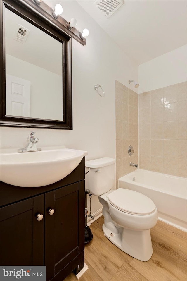 full bath featuring toilet, visible vents, wood finished floors, and vanity