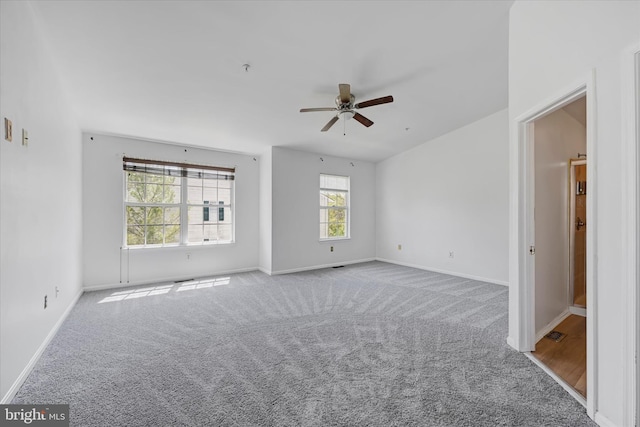 carpeted spare room featuring ceiling fan and baseboards