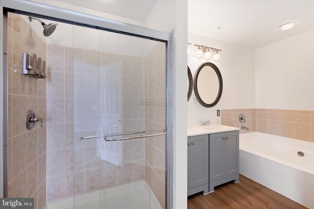 bathroom featuring vanity, a bath, a shower stall, and wood finished floors