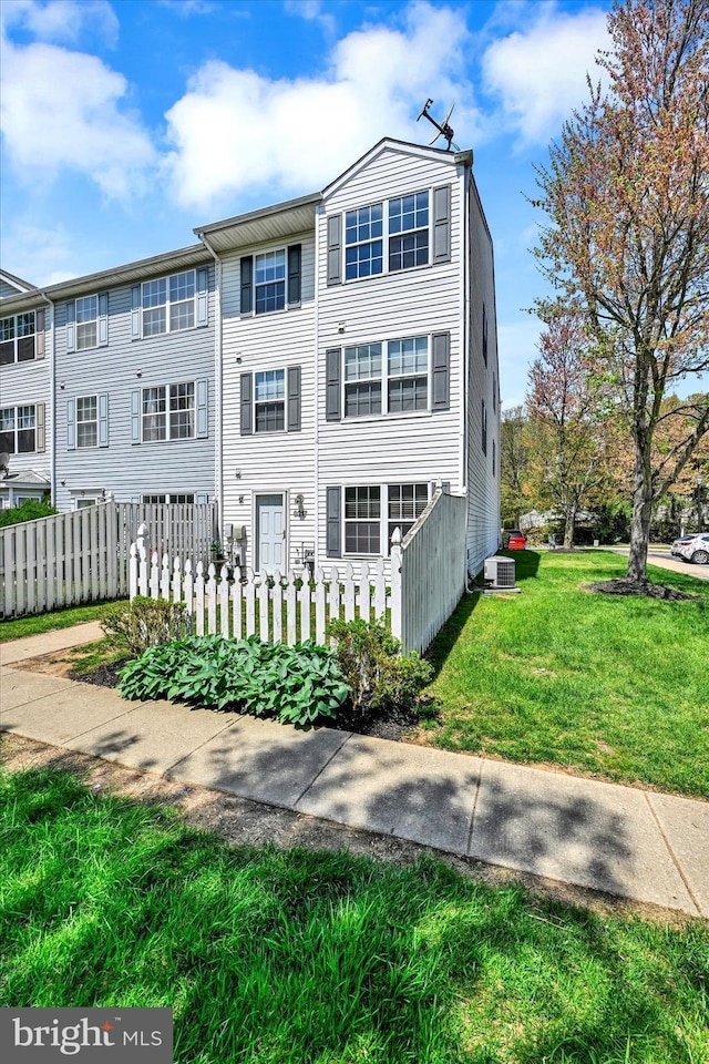 view of property featuring fence, central AC unit, and a front yard