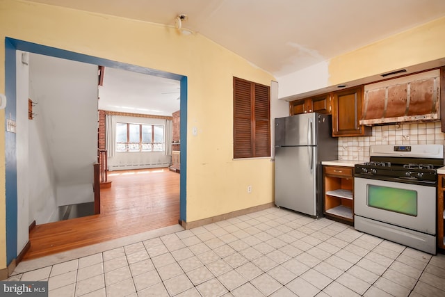 kitchen featuring baseboards, light countertops, tasteful backsplash, appliances with stainless steel finishes, and vaulted ceiling