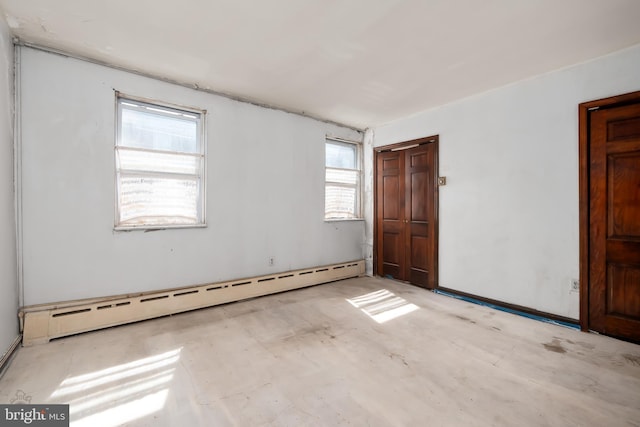 spare room with a baseboard heating unit and unfinished concrete floors