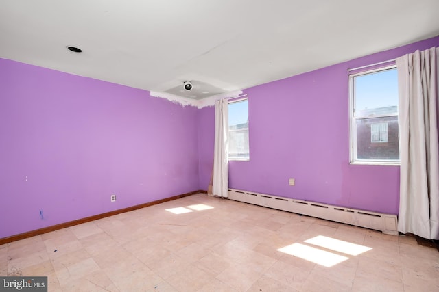 empty room with baseboards, a healthy amount of sunlight, baseboard heating, and tile patterned floors