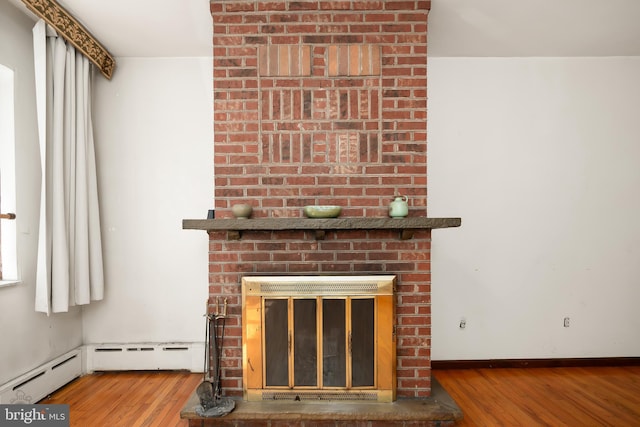 room details featuring a brick fireplace, baseboard heating, baseboards, and wood finished floors