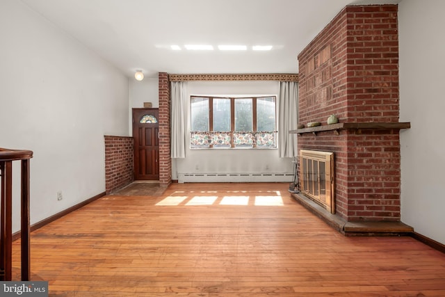 unfurnished living room with baseboards, a baseboard radiator, a brick fireplace, and light wood-style flooring