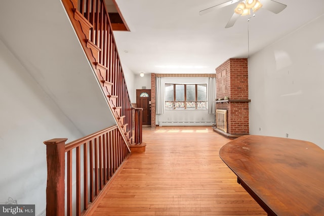 entrance foyer featuring hardwood / wood-style flooring, ceiling fan, a baseboard heating unit, and stairs