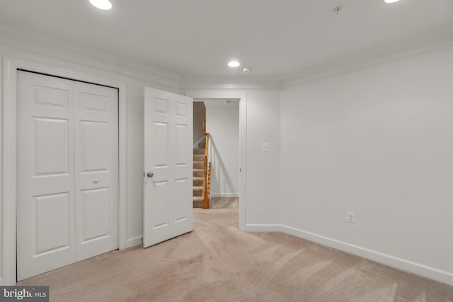 below grade area featuring light carpet, ornamental molding, baseboards, stairs, and recessed lighting