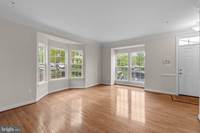 foyer entrance with light wood-style flooring, baseboards, and crown molding