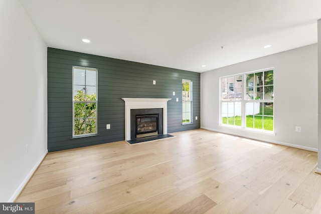 unfurnished living room featuring recessed lighting, baseboards, a glass covered fireplace, and wood finished floors