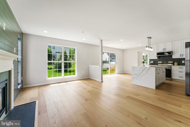 kitchen with a kitchen island, appliances with stainless steel finishes, a fireplace, open floor plan, and light wood-style floors