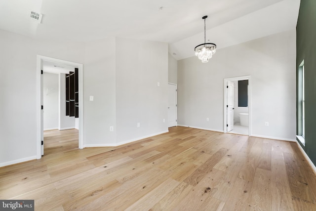 unfurnished room with baseboards, an inviting chandelier, visible vents, and light wood-type flooring