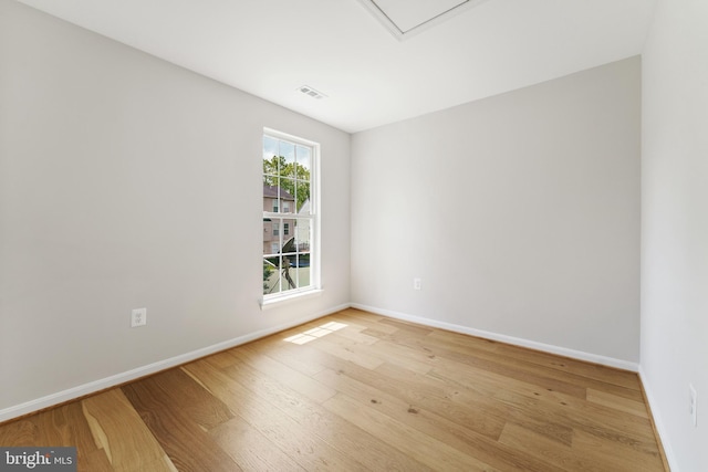 unfurnished room featuring baseboards, visible vents, and wood finished floors