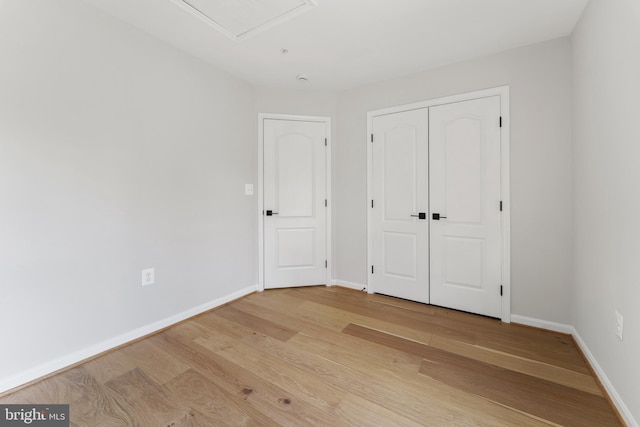 unfurnished bedroom with baseboards, light wood finished floors, and a closet