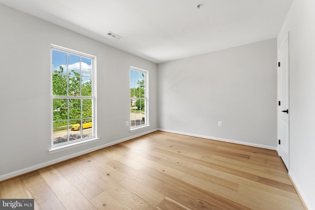 unfurnished room with visible vents, light wood-style floors, and baseboards