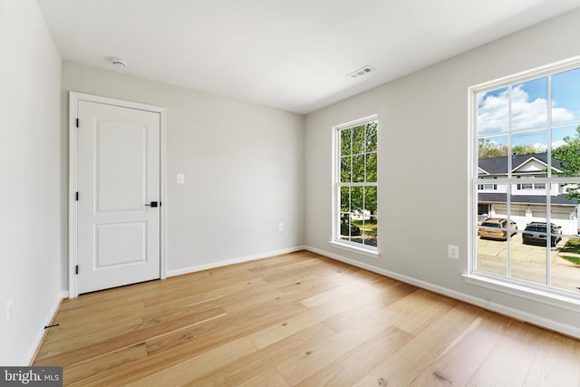 unfurnished room featuring baseboards, light wood-style flooring, and visible vents