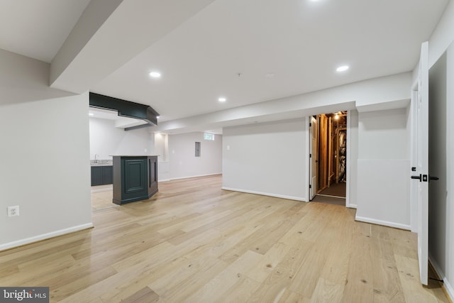 finished basement with recessed lighting, light wood-style flooring, baseboards, and wet bar
