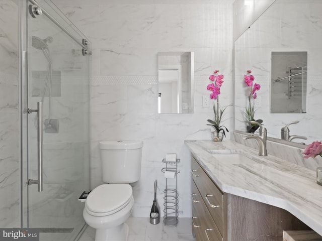 bathroom with vanity, toilet, a marble finish shower, marble finish floor, and tile walls