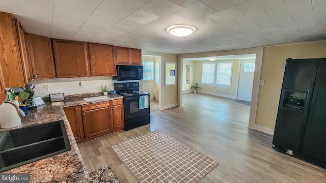 207 Spruce St, Westernport, MD 21562 - kitchen featuring brown cabinetry, a sink, black appliances, and light wood finished floors