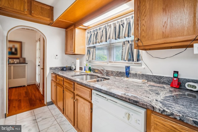 5506 39th Ave, Hyattsville, MD 20781 - kitchen featuring dishwasher, a sink, arched walkways, dark stone counters, and brown cabinetry