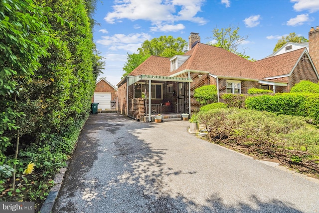 5506 39th Ave, Hyattsville, MD 20781 - view of front facade featuring a chimney, brick siding, an outbuilding, asphalt driveway, and a shingled roof