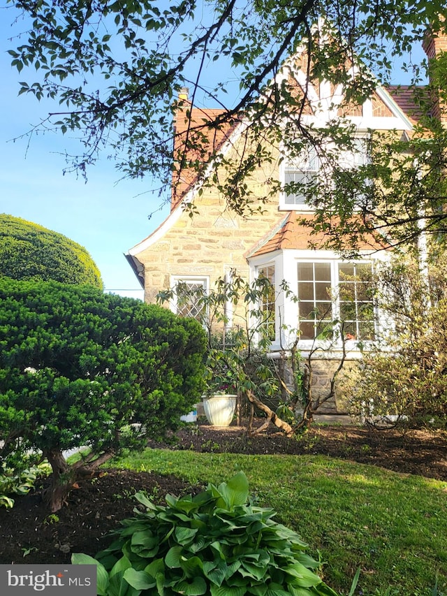 view of side of property featuring a chimney and stone siding