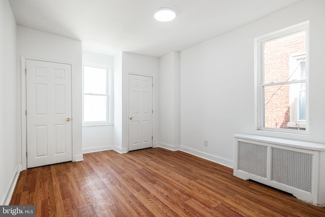 unfurnished room with baseboards, wood finished floors, and radiator