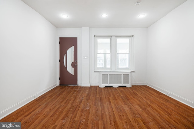 entryway with recessed lighting, baseboards, wood finished floors, and radiator