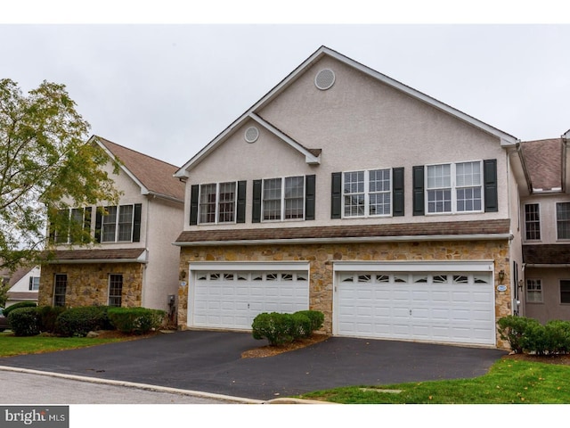 multi unit property featuring a garage, stucco siding, aphalt driveway, and stone siding