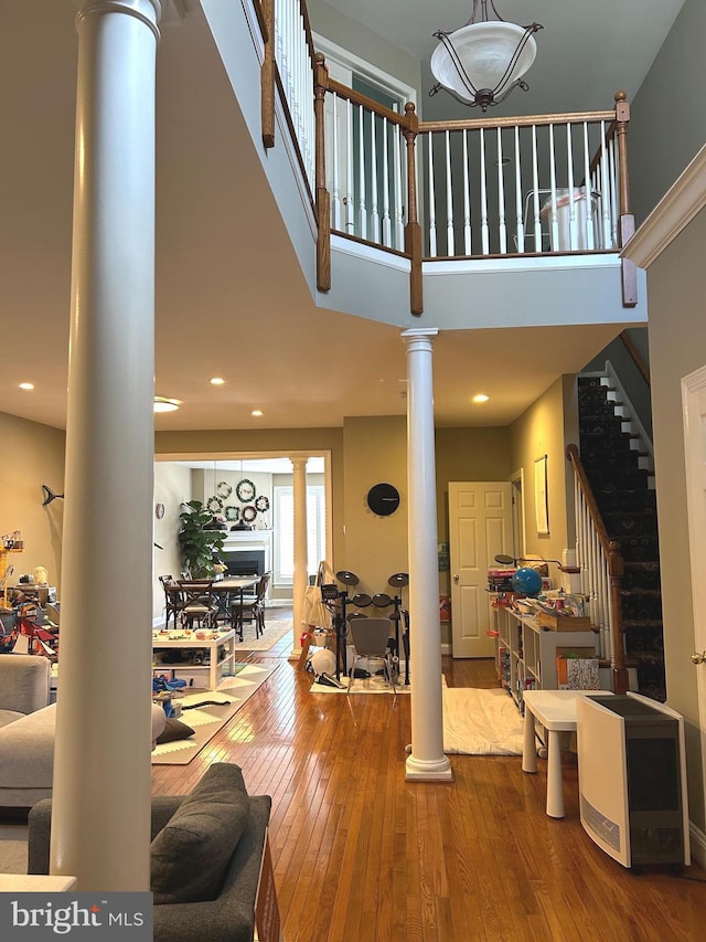 interior space with stairs, a high ceiling, decorative columns, and hardwood / wood-style flooring