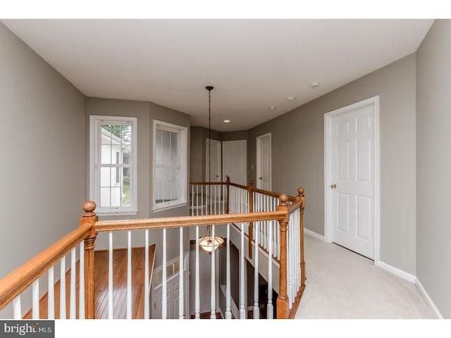 corridor with baseboards, carpet flooring, and an upstairs landing