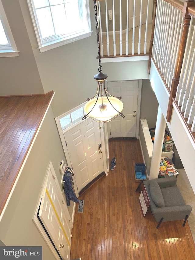 foyer featuring stairway, plenty of natural light, dark wood-style floors, and visible vents