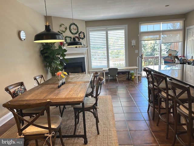 dining area with a fireplace and dark tile patterned flooring