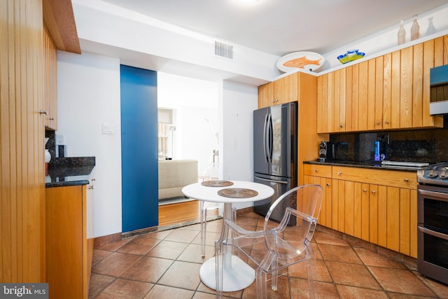 kitchen featuring dark countertops, decorative backsplash, stainless steel appliances, and visible vents