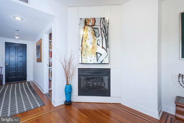 entrance foyer with recessed lighting, baseboards, a glass covered fireplace, and wood finished floors