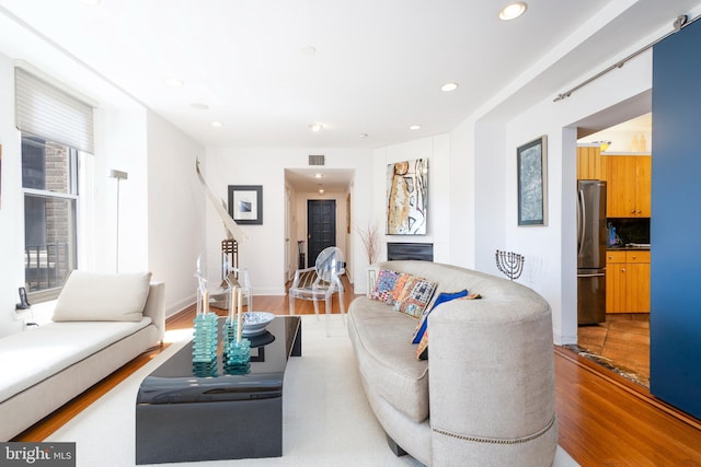 living room with recessed lighting, wood finished floors, and visible vents