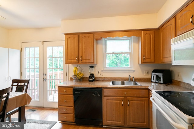 kitchen with a sink, brown cabinetry, white appliances, light wood finished floors, and light countertops