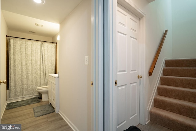 bathroom featuring toilet, baseboards, wood finished floors, and vanity