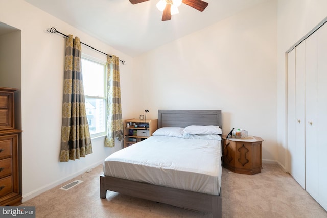 bedroom featuring a closet, visible vents, vaulted ceiling, ceiling fan, and light carpet