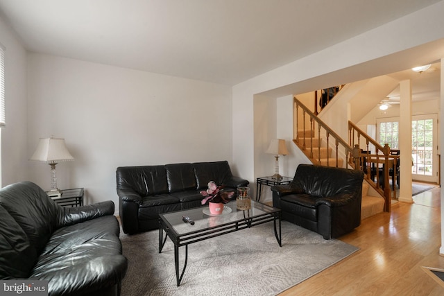 living area with a ceiling fan, stairs, and wood finished floors