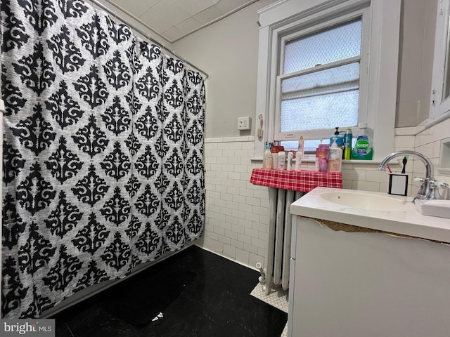 full bathroom with vanity, tile walls, a shower with shower curtain, and a wainscoted wall