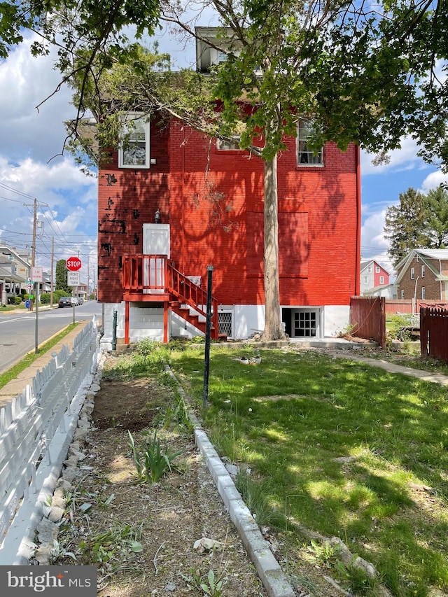 view of side of home with fence, brick siding, and a lawn
