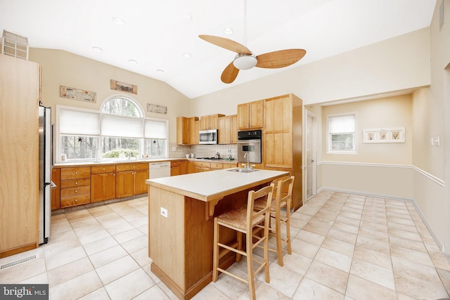 kitchen with ceiling fan, a breakfast bar area, vaulted ceiling, light countertops, and stainless steel appliances