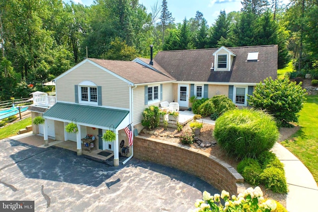 view of front of home with covered porch, driveway, and a shingled roof