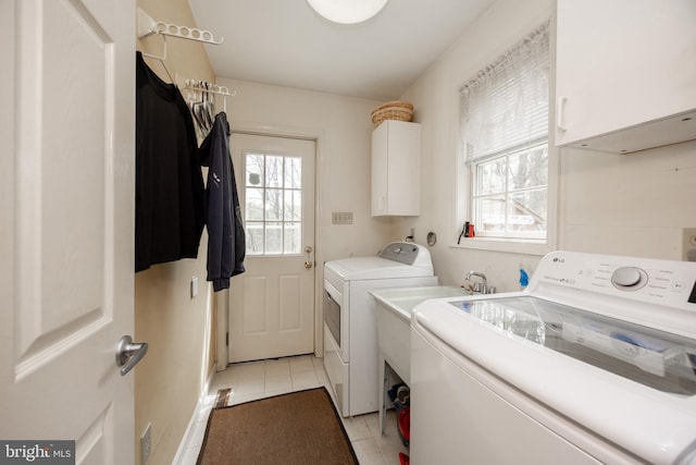clothes washing area with cabinet space, light tile patterned floors, and washer and dryer