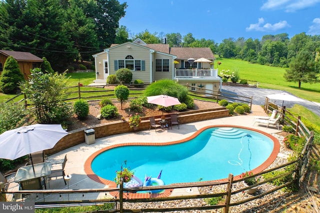 outdoor pool with a patio, a lawn, and fence