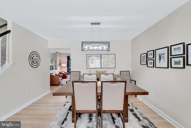 dining room featuring baseboards, light wood finished floors, and a chandelier