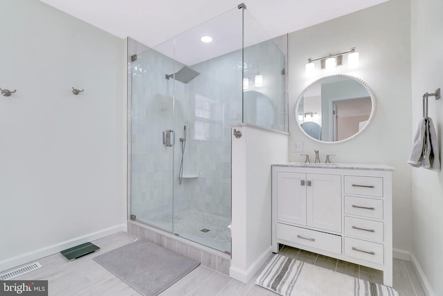 bathroom with vanity, baseboards, a shower stall, and wood finished floors