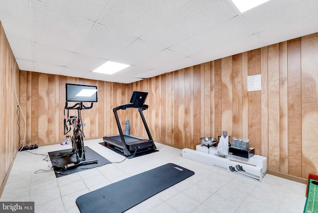 workout room featuring wooden walls and a drop ceiling