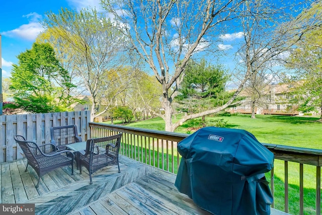 wooden terrace featuring a yard and a grill